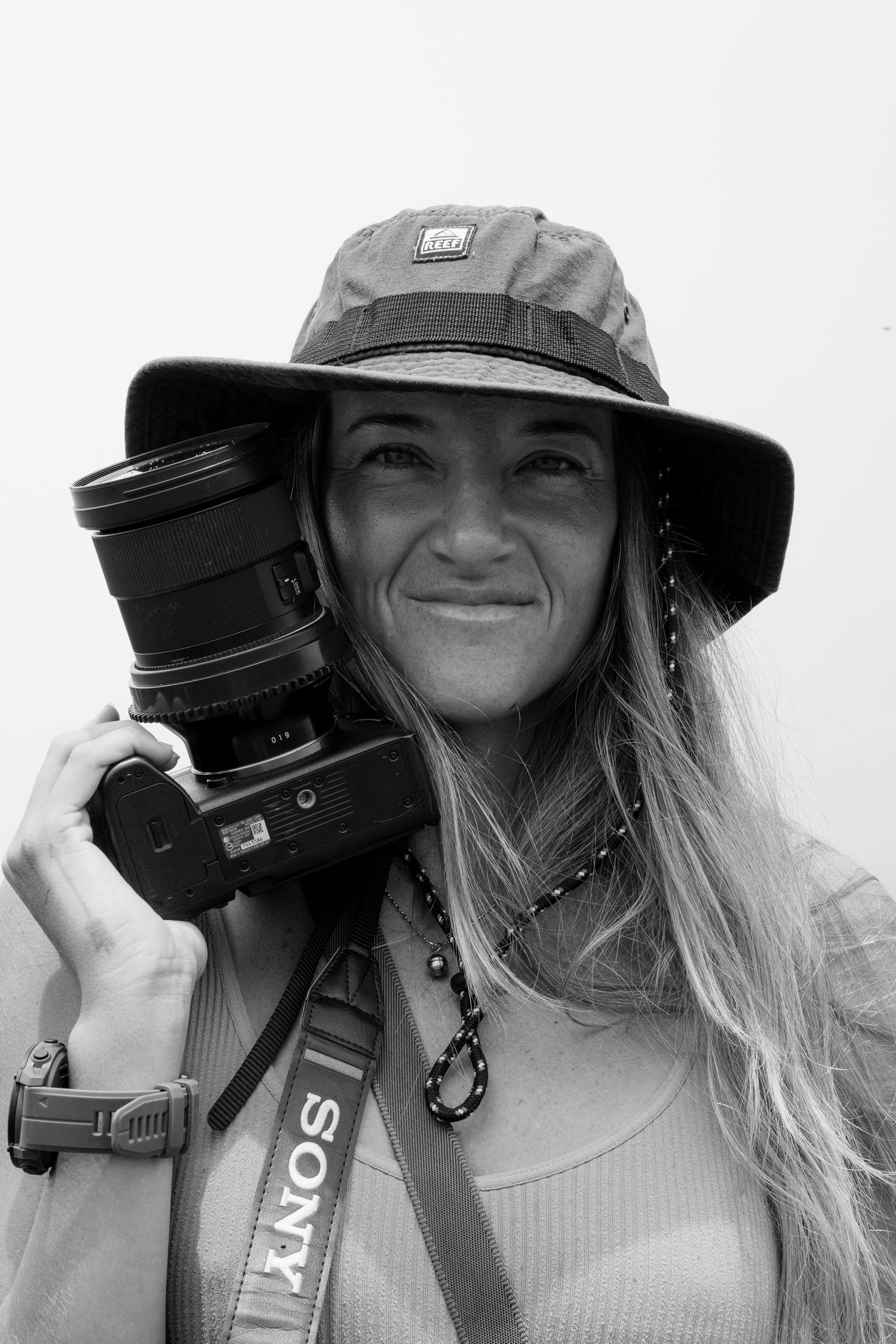 Portrait of a photographer with camera equipment wearing a sun hat.