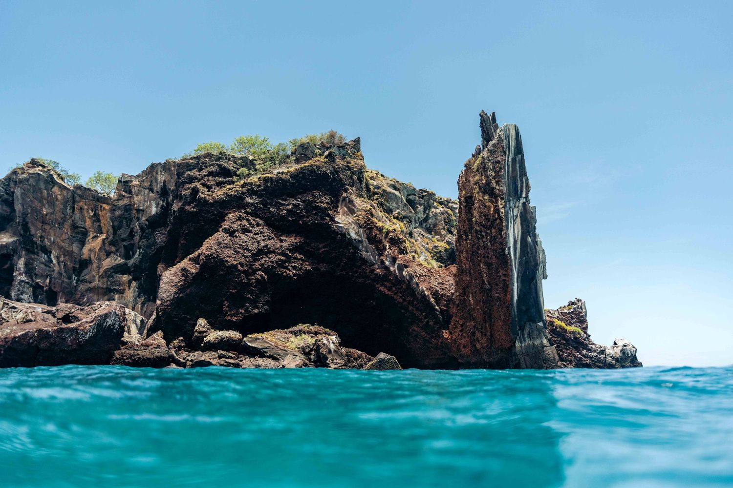Scenic panoramic view of rugged coastal cliffs and turquoise blue ocean waters under bright sunny skies.