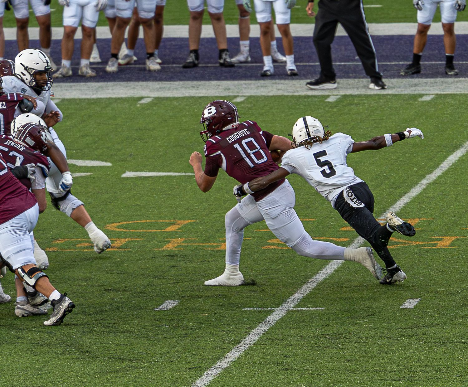 Football players engage in a running play on the field during a competitive game.