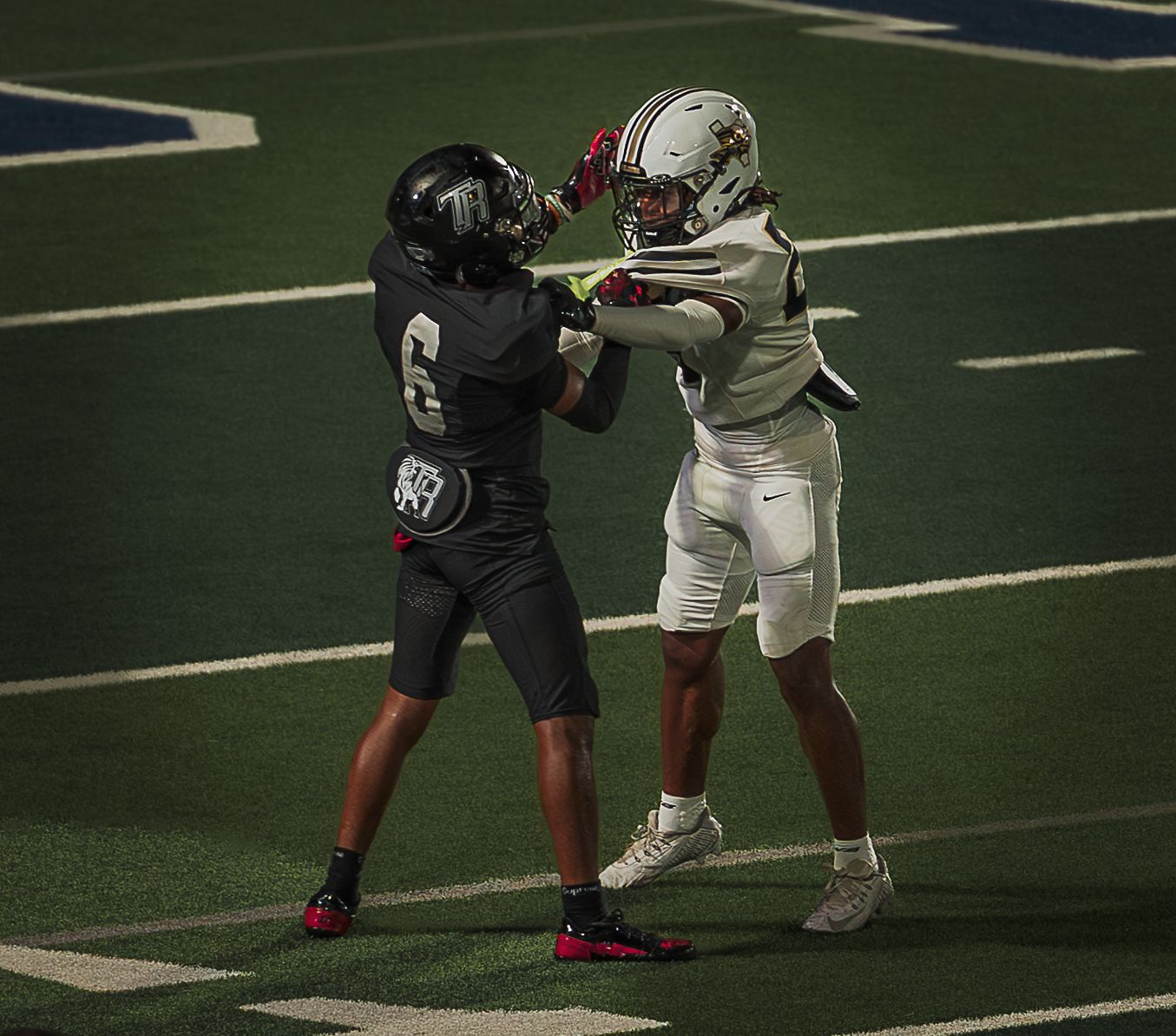 Football players in contrasting uniforms face off during a play on the field.