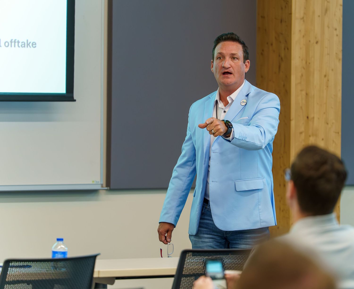 Presenter in light blue blazer speaking animatedly during a business presentation.