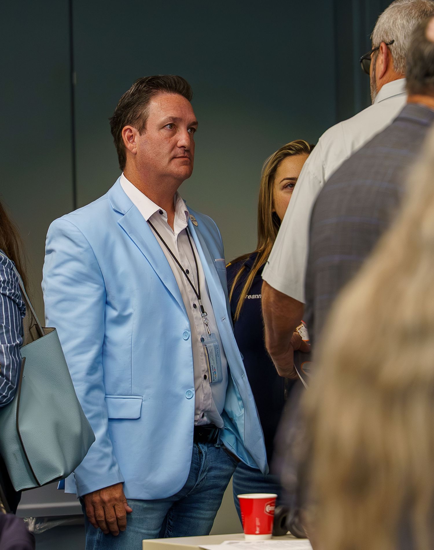 Person wearing a light blue blazer standing in a conference room setting.