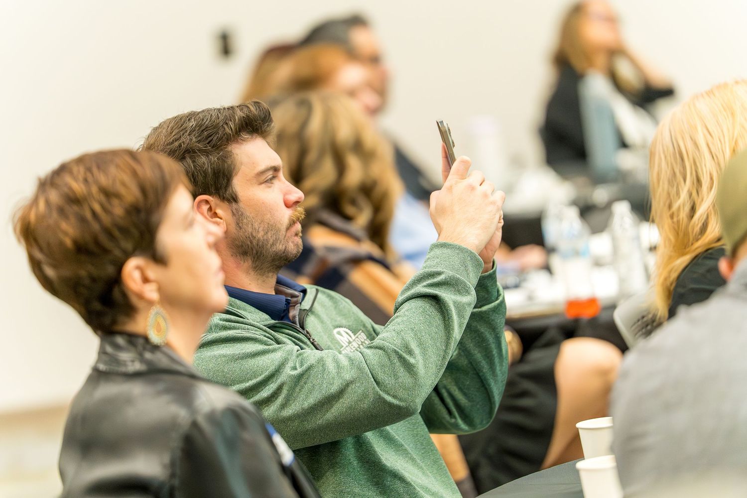 Side view of audience members seated during an event presentation.