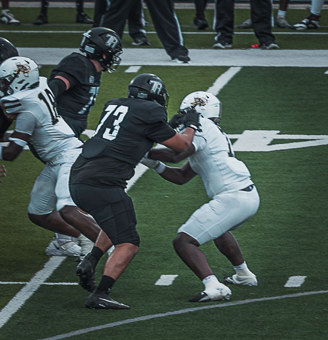 Football players clash at the line of scrimmage during an intense game play.