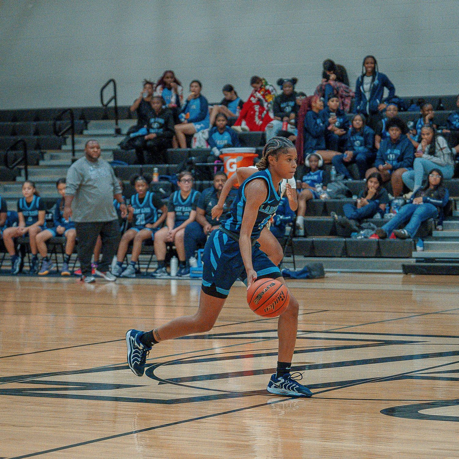 Basketball player performs a sliding defensive move across the hardwood court during an indoor game.