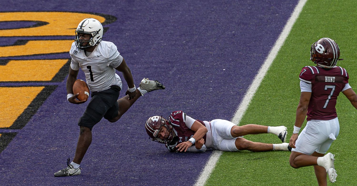 Football player evades a diving tackle attempt near the goal line during a college football game.