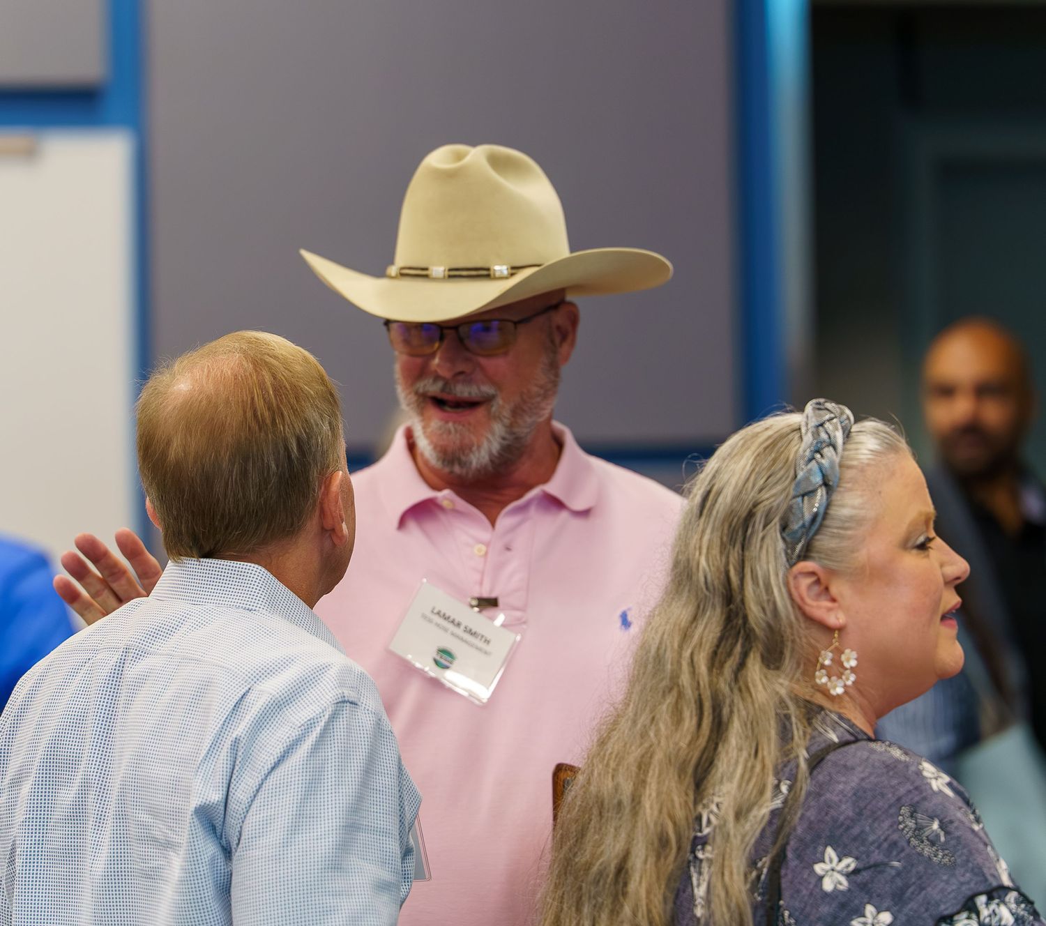 Casual networking conversation between attendees, with one wearing a cowboy hat.