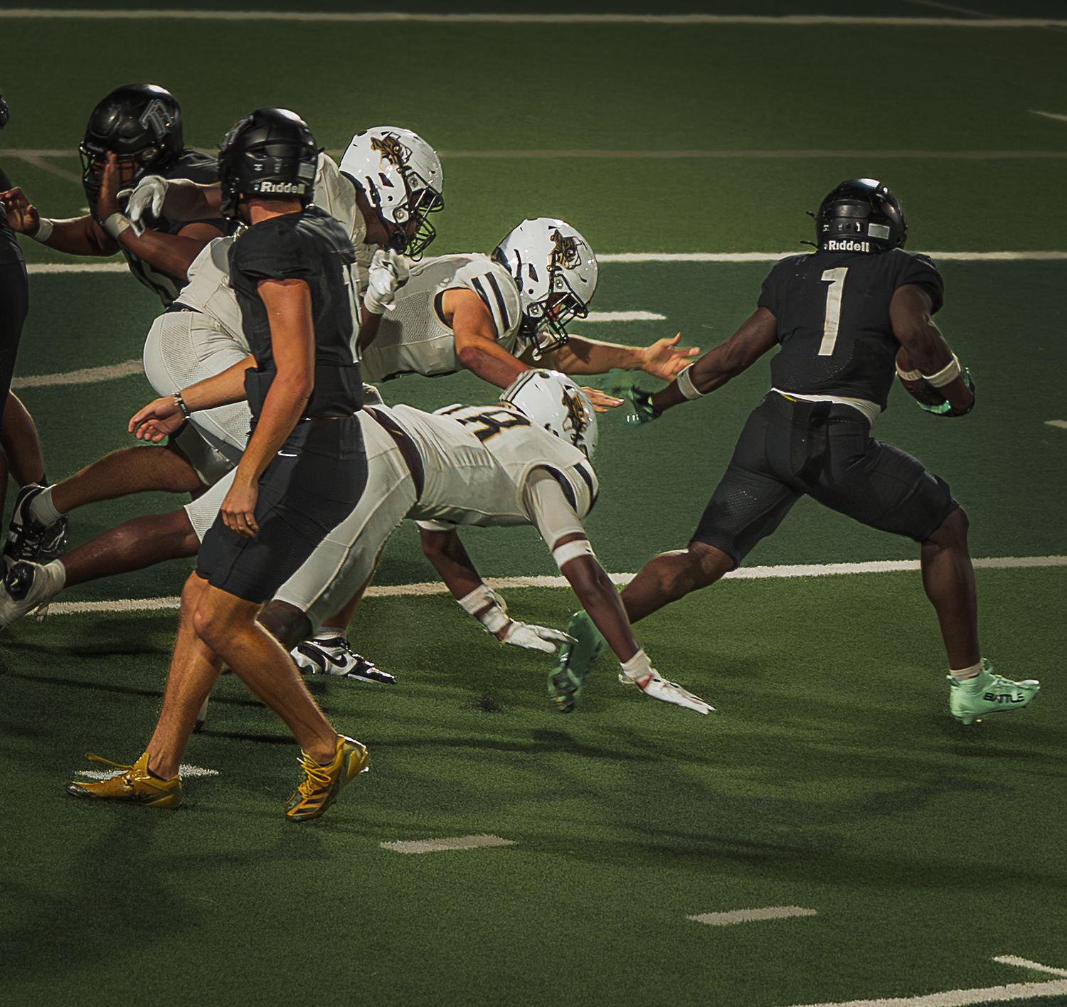 Football players in black and white uniforms compete for position during an intense game play on the field.