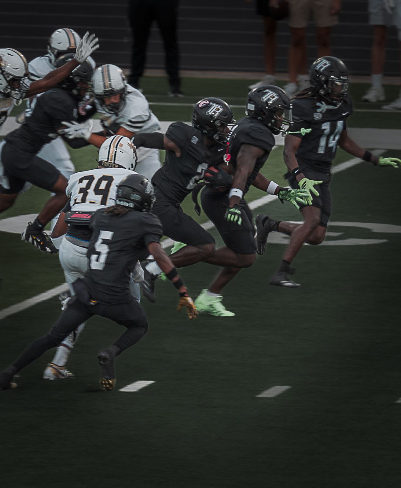 Football players in black and white uniforms engage in a defensive play on the field.