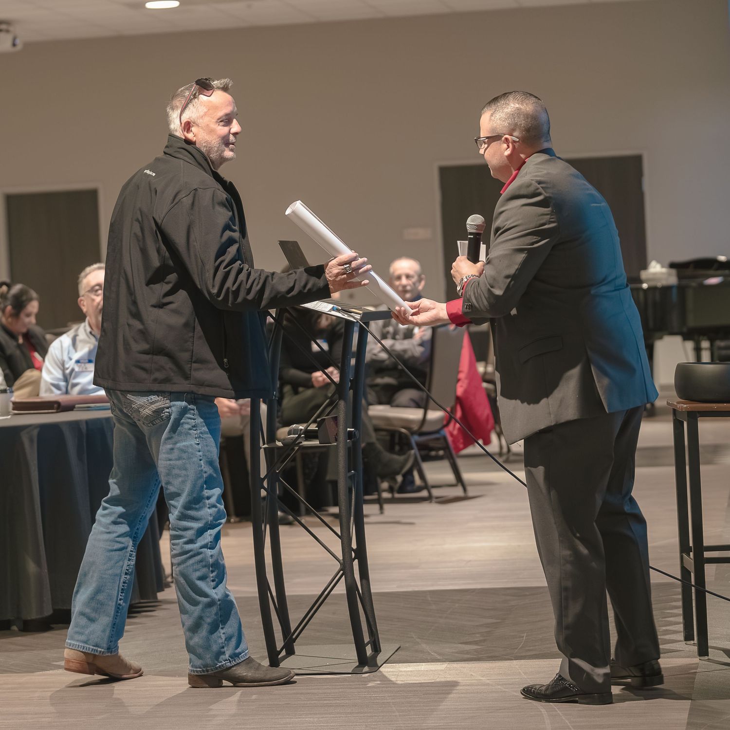 Two people interacting at podium during business event.