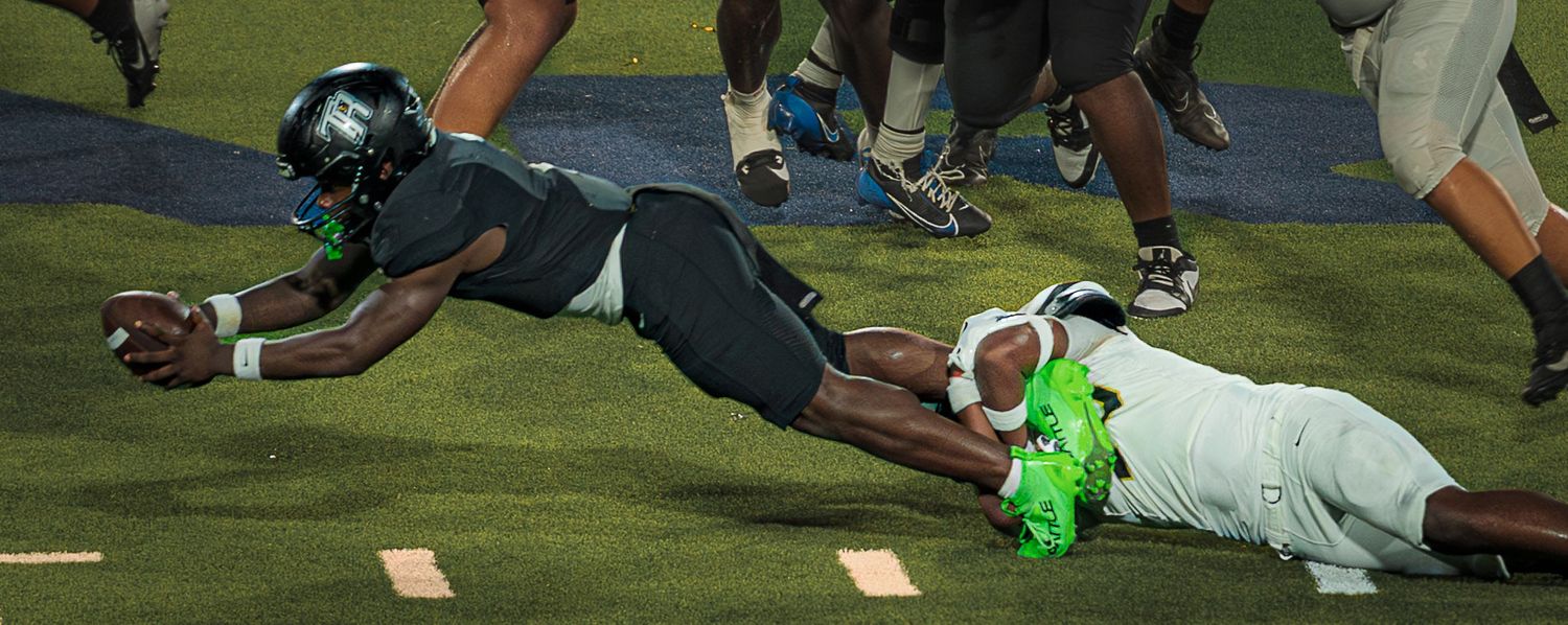 Football players engage in ground-level action during an intense play.