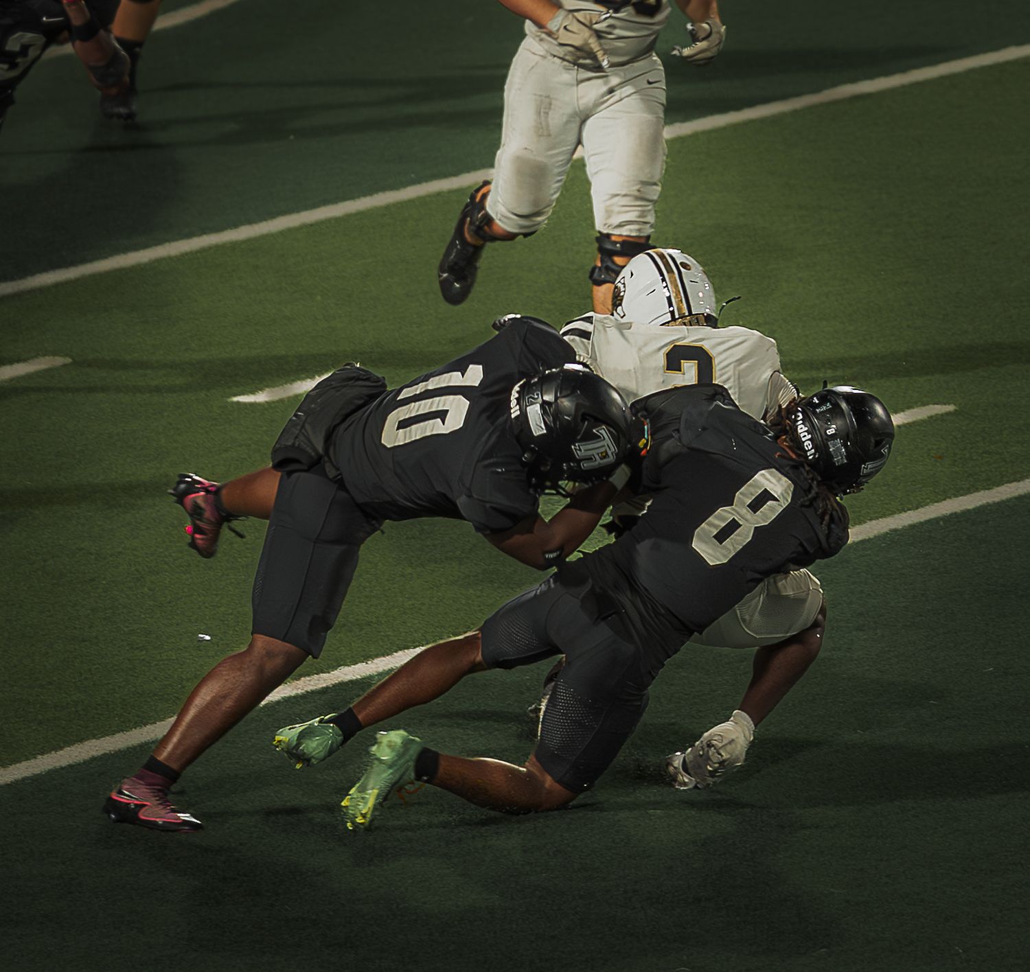 A football player makes a diving catch during a game on the field.