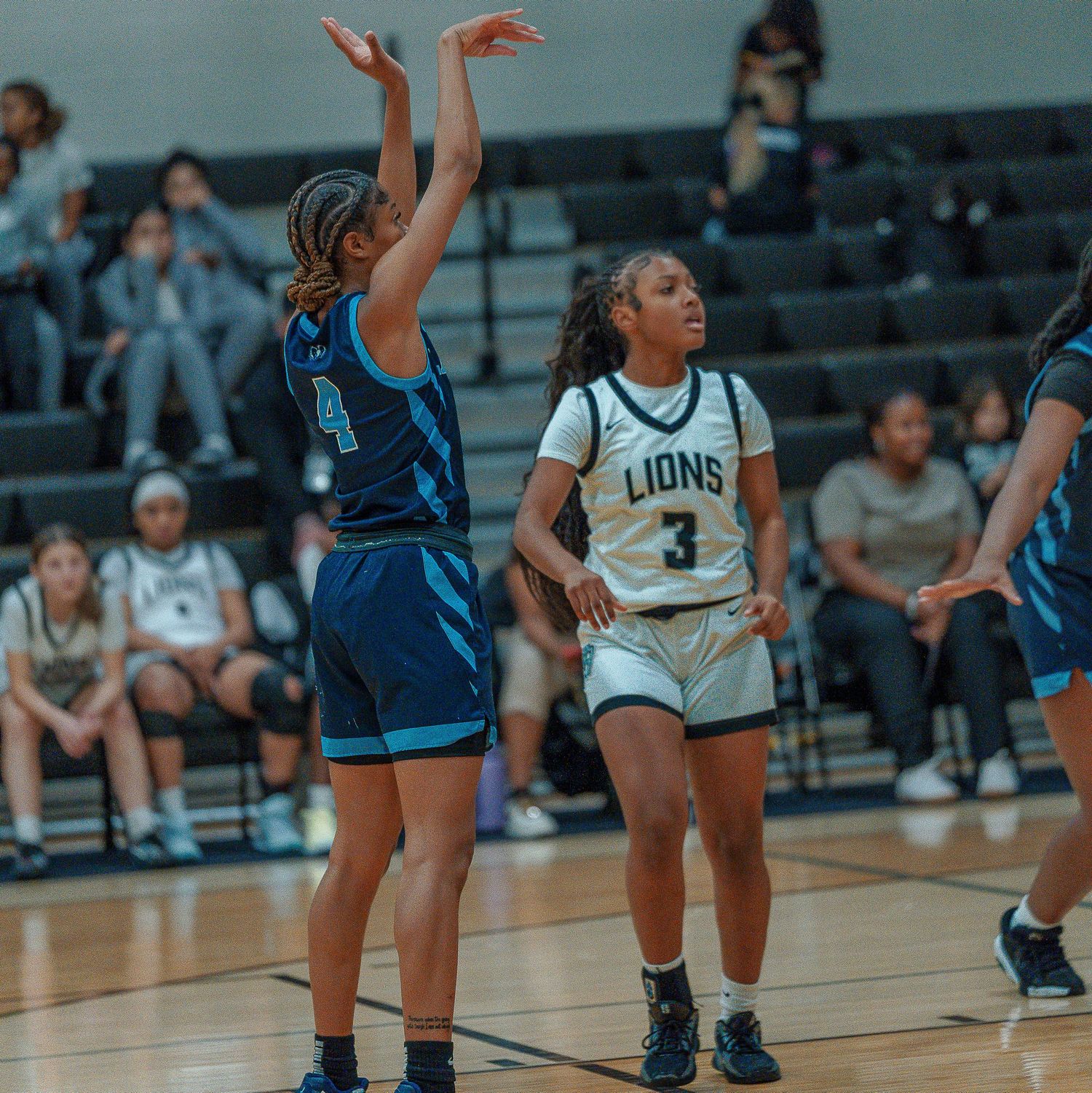 Basketball players from opposing teams compete during a game with one player attempting a shot in a gymnasium.