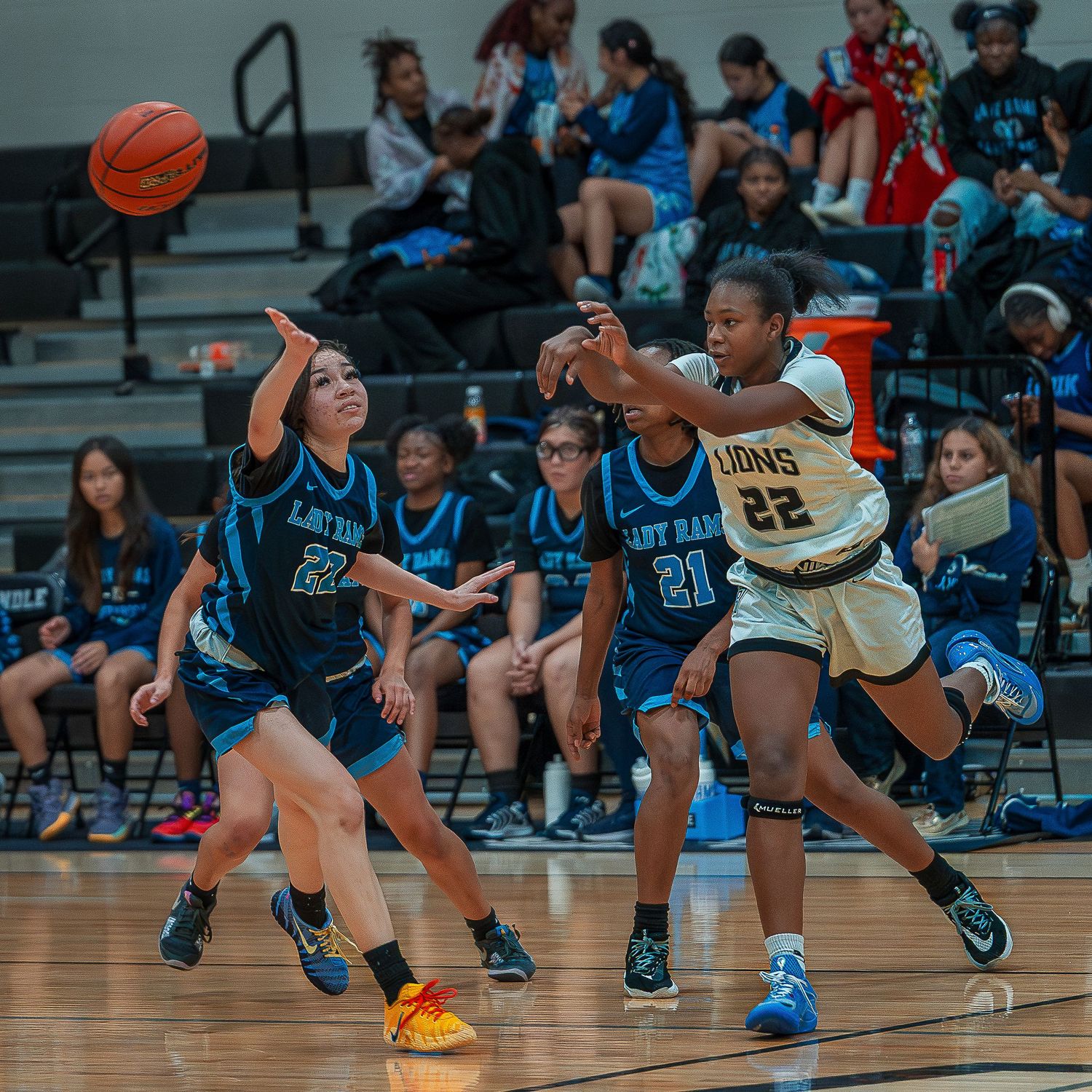 Basketball players dive and scramble for a loose ball during an intense game on a gymnasium court.