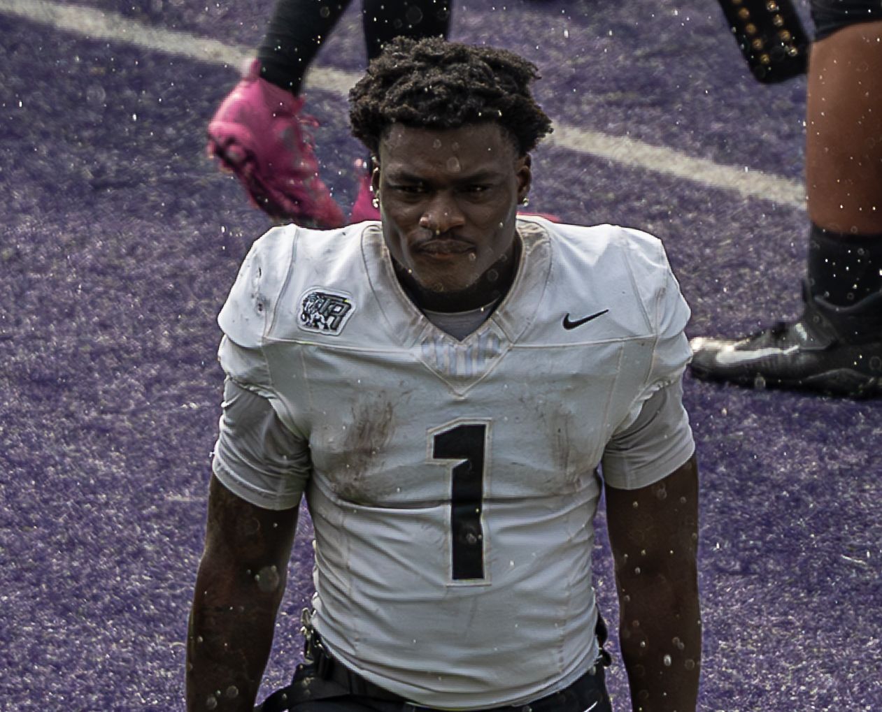Football player in white jersey number 1 on field during game action.