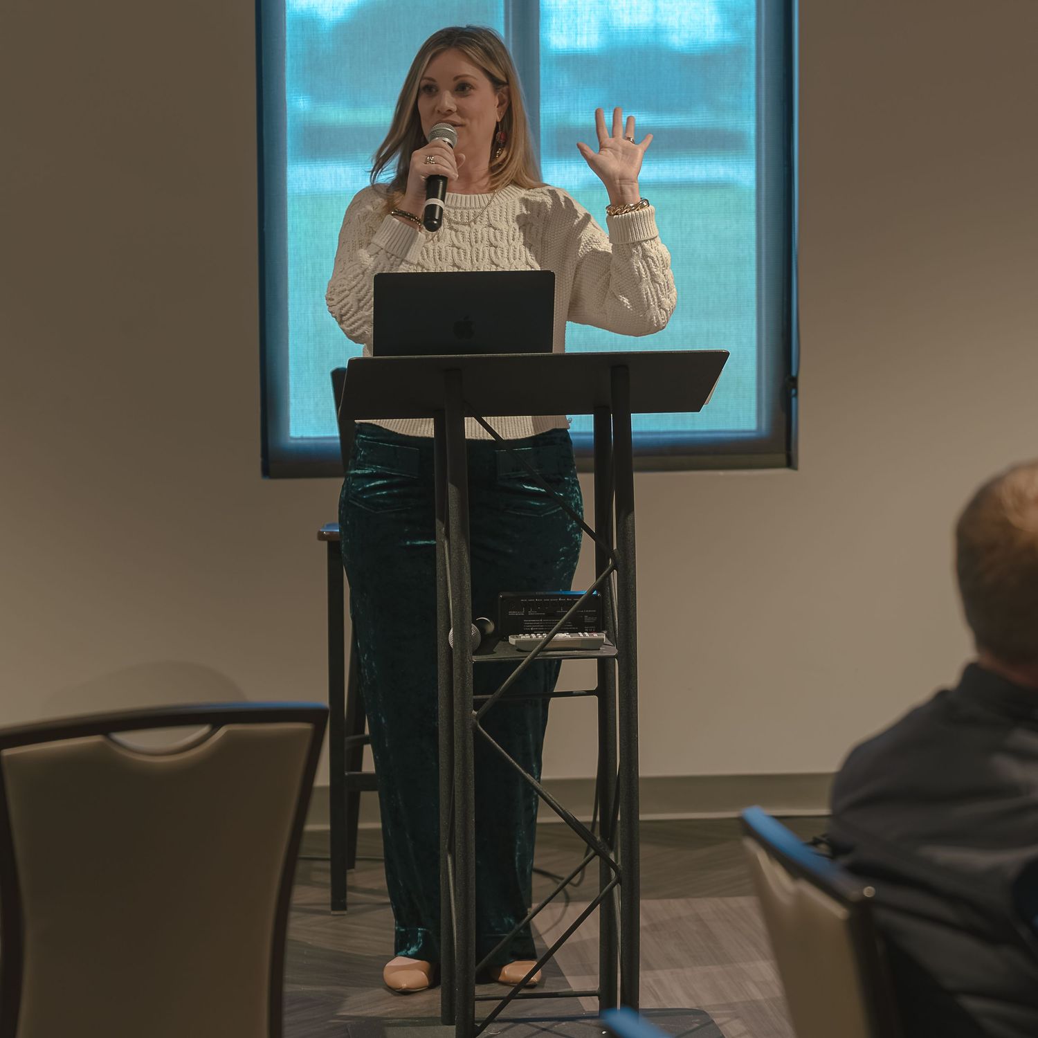 Speaker presenting from a podium in front of a window.