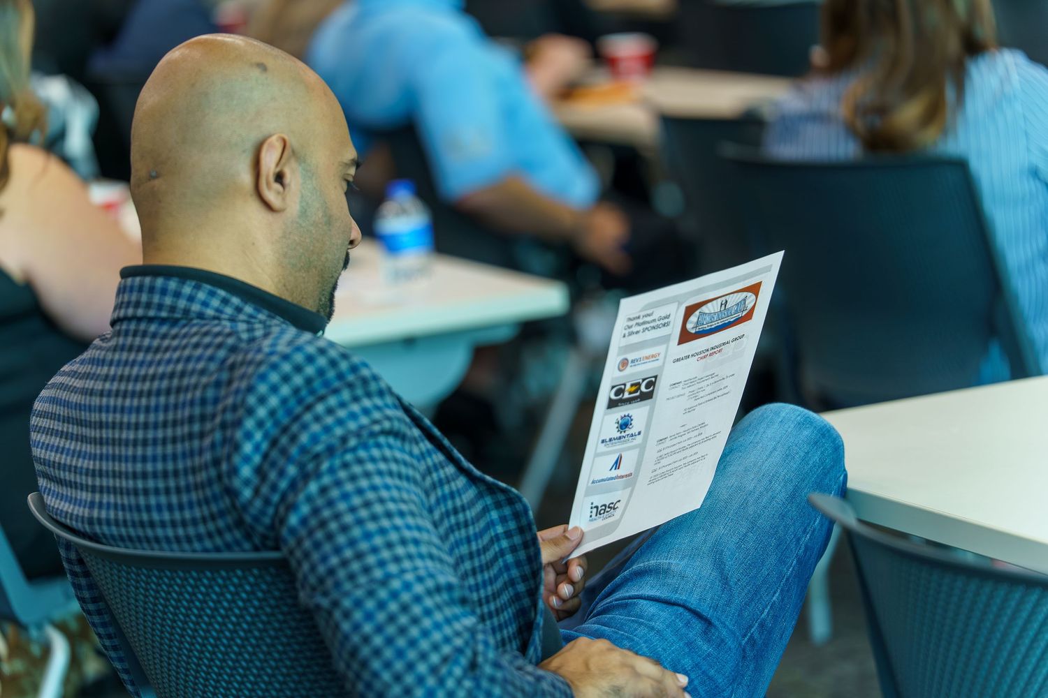 People seated at tables reviewing documents during a meeting or conference.