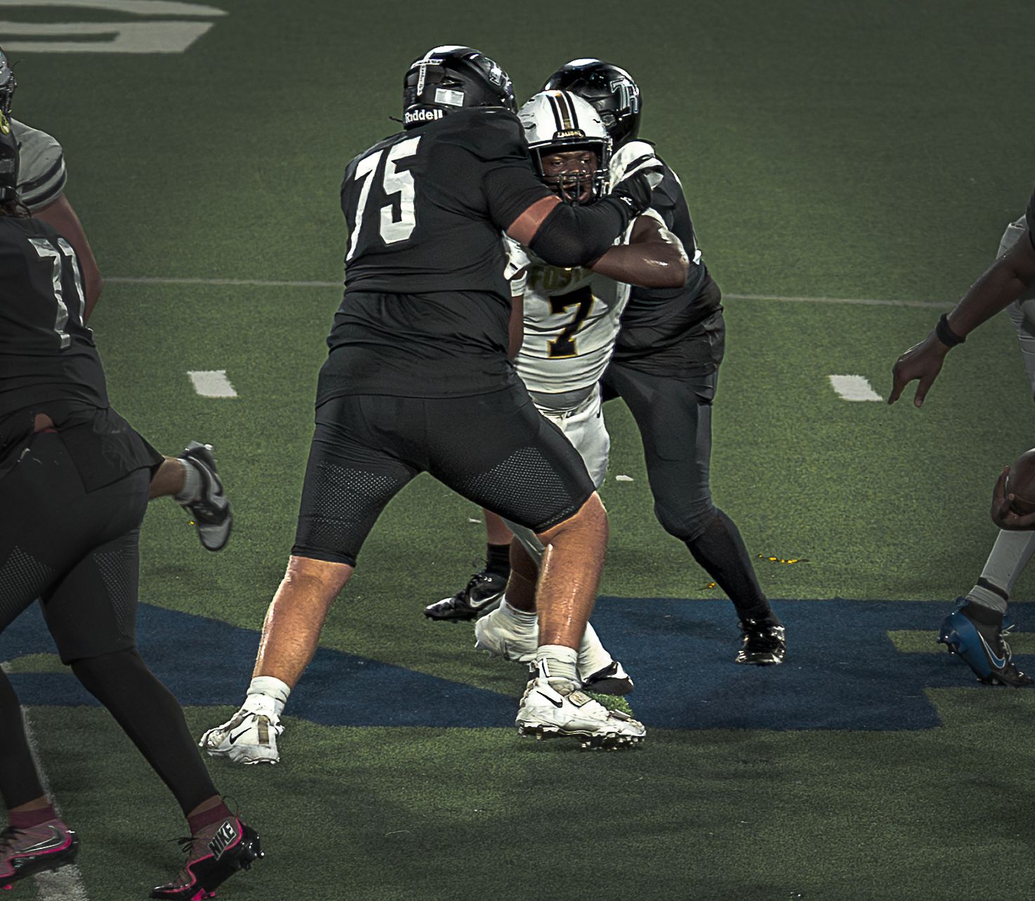 Close-up view of football players' cleats and legs during a game on artificial turf field.
