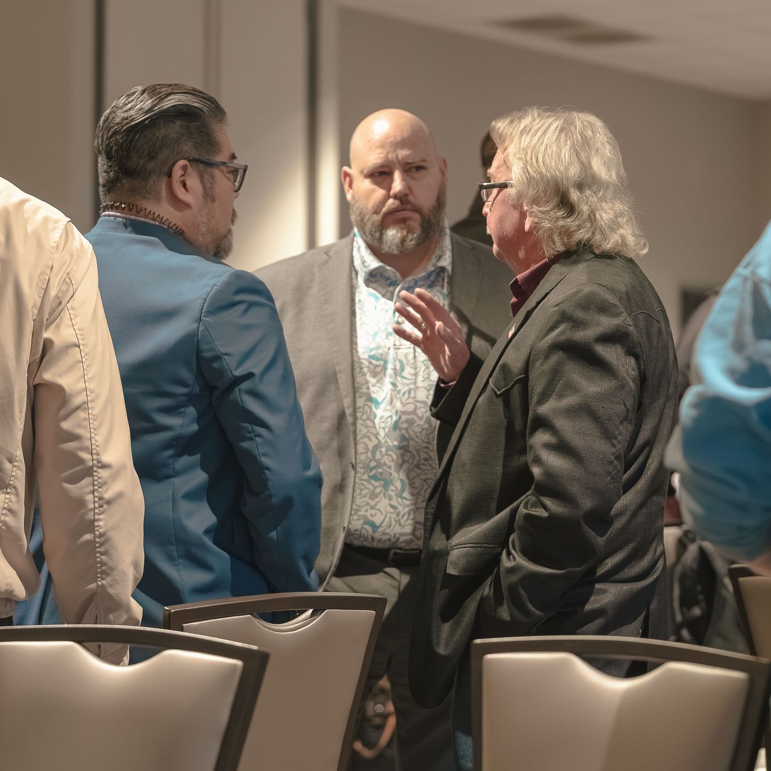 Three people engaged in animated discussion during a professional conference or meeting.