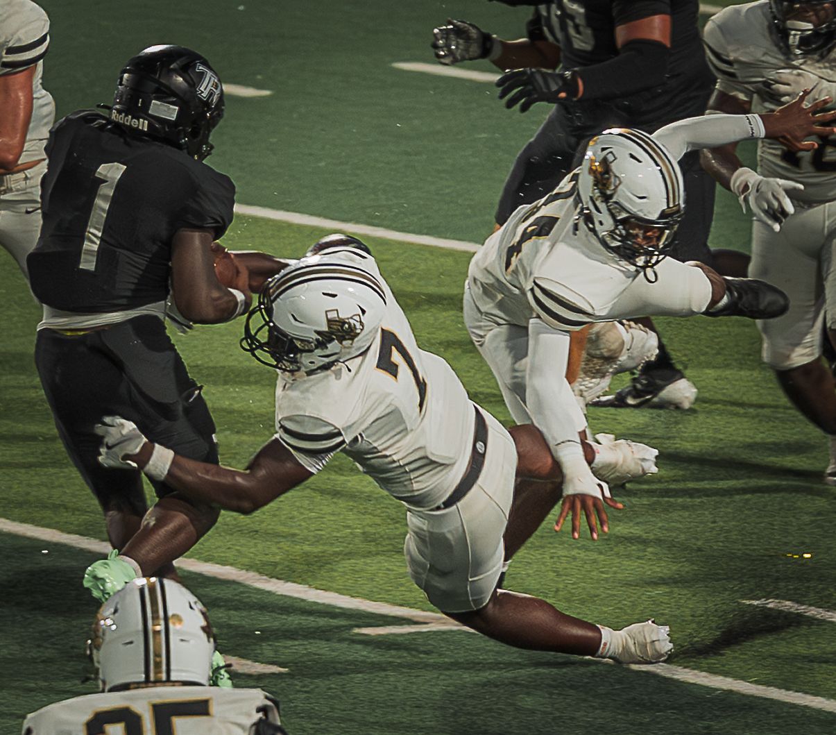 Football players from opposing teams collide during an intense play on the field.
