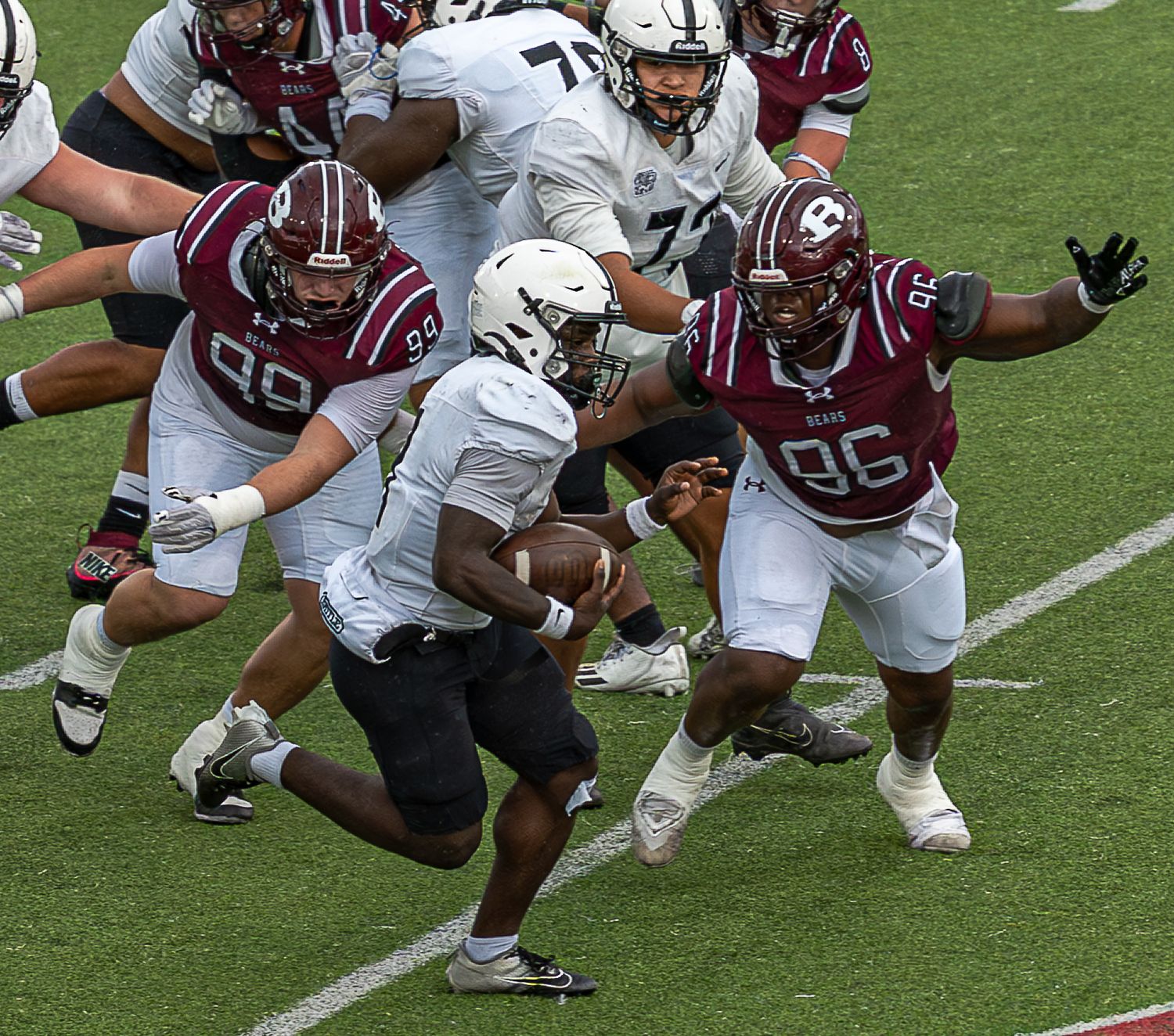 Football players in red and white uniforms scramble for a loose ball during a college football game.