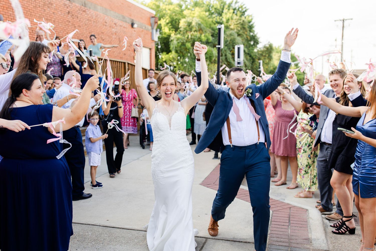 A wedding couple celebrates with guests on a city street during their exit.