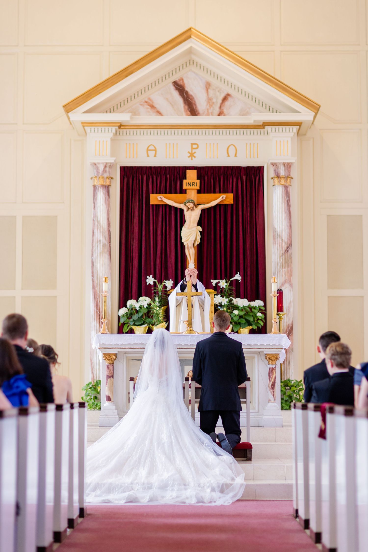 A couple stands at the altar during their Catholic church wedding ceremony.