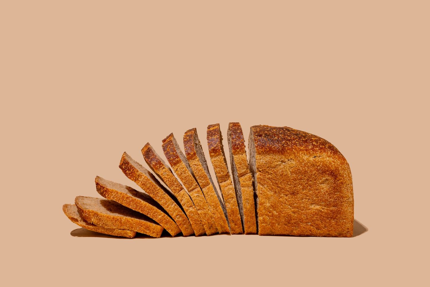 Sequential shots of sliced rustic bread loaf on beige background.