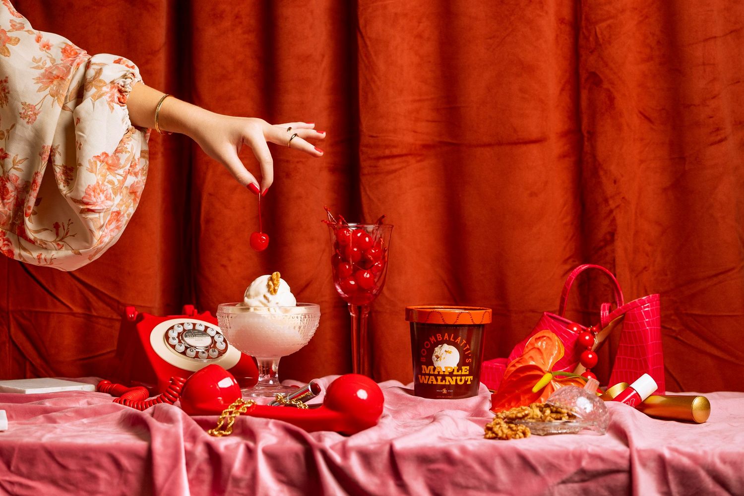 Elegant table setting with whipped cream desserts and red decorative elements against red curtain backdrop.