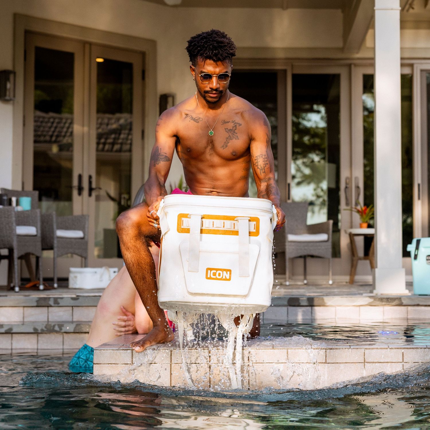 White cooler making splash in pool water during outdoor lifestyle photoshoot.