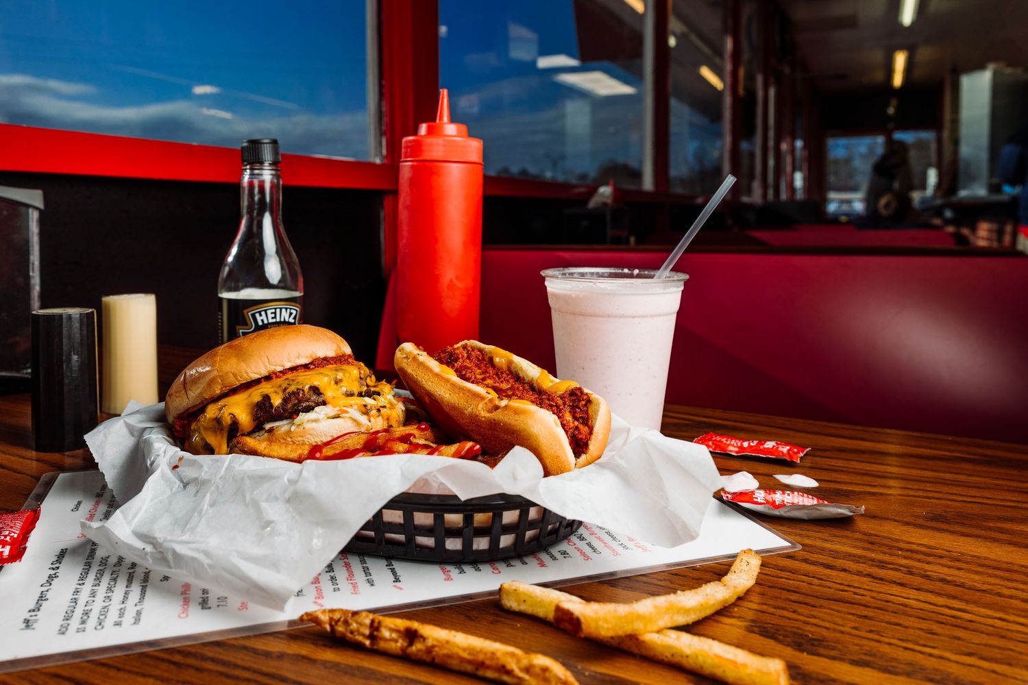 Classic diner spread with hamburger, hot dog, and fries on paper-lined table.