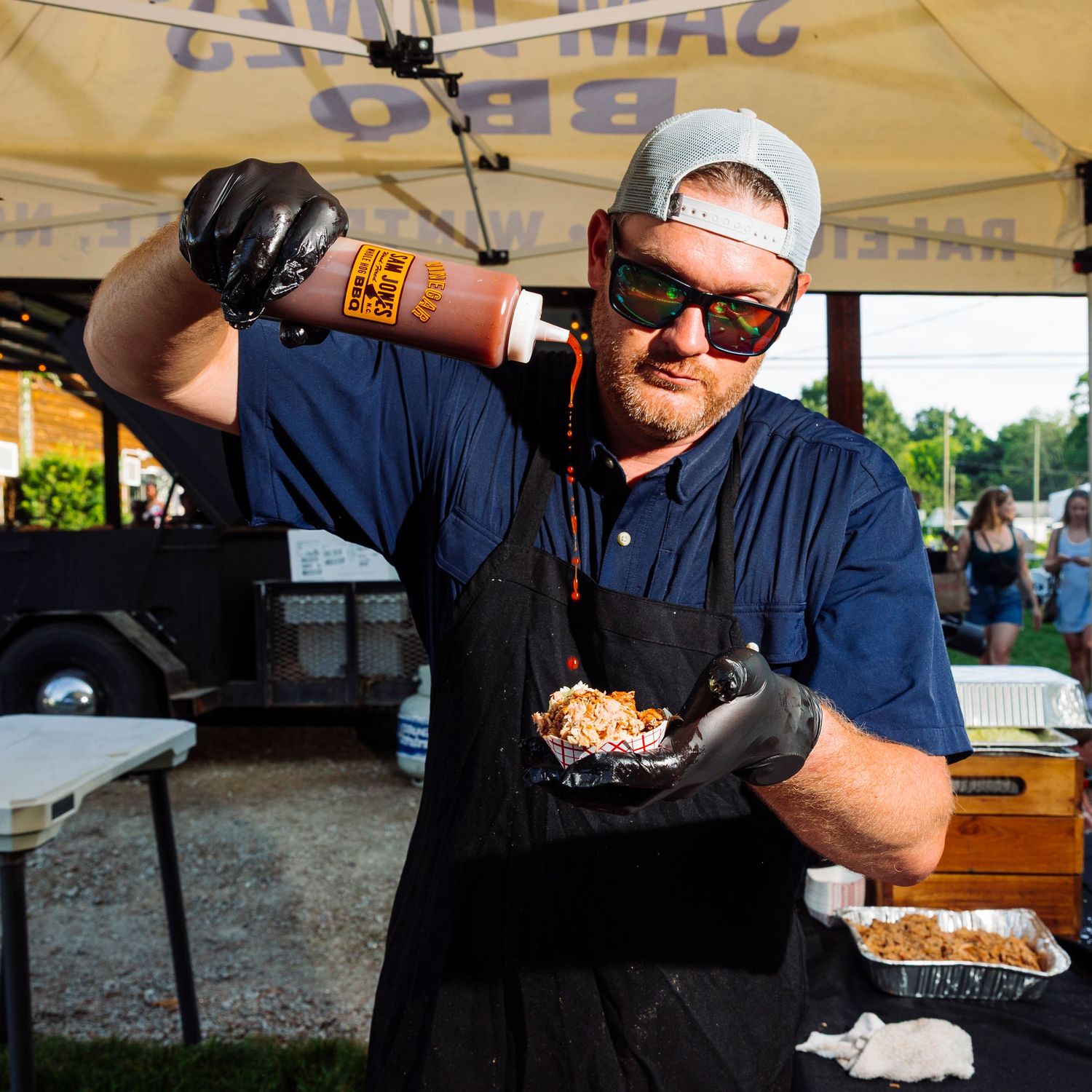 People preparing and serving food at an outdoor festival tent.
