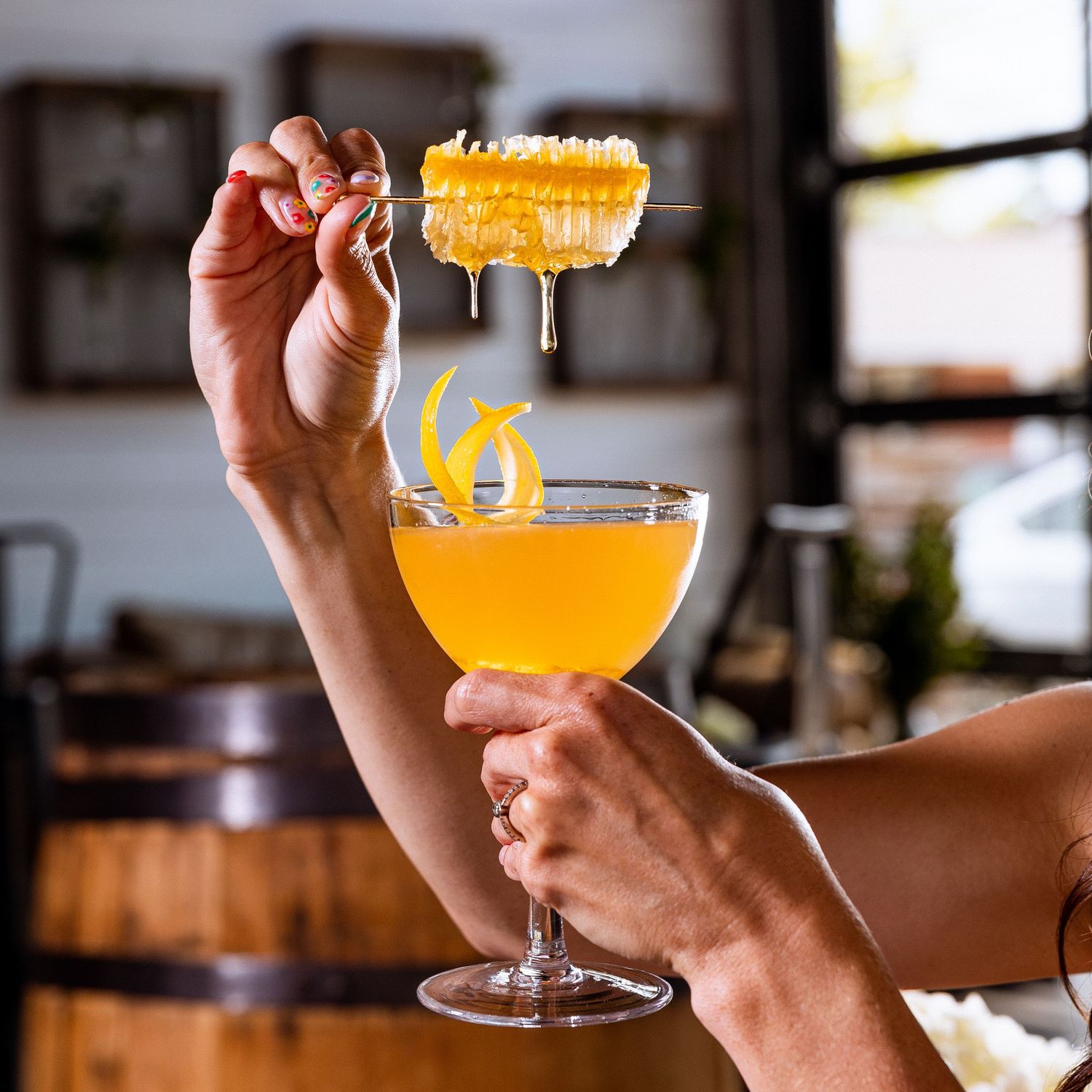 Orange cocktails with foam being held up in elegant glassware at an upscale bar.