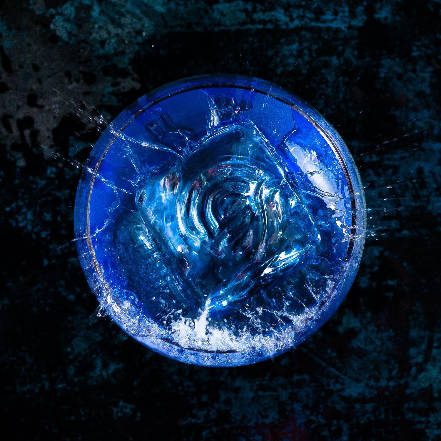 Abstract blue water splash patterns captured in dramatic lighting against dark background.