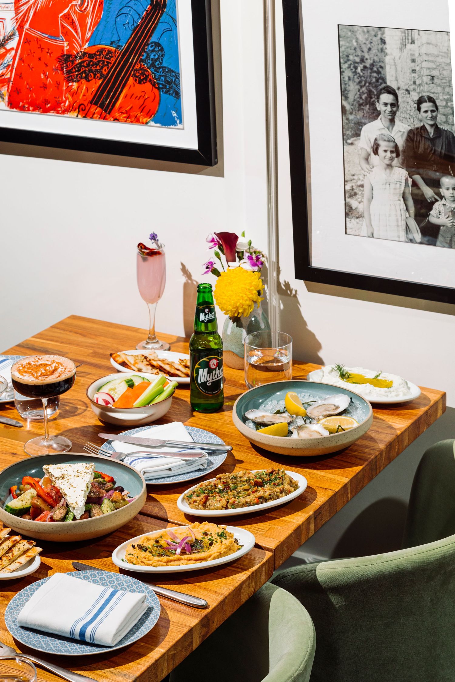 Elegant dinner table setting with cocktails, seafood dishes and framed artwork on wall.