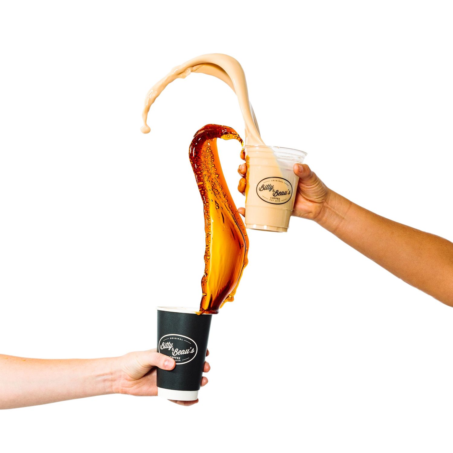 Hands pouring golden beer creating perfect foam head in branded glassware.