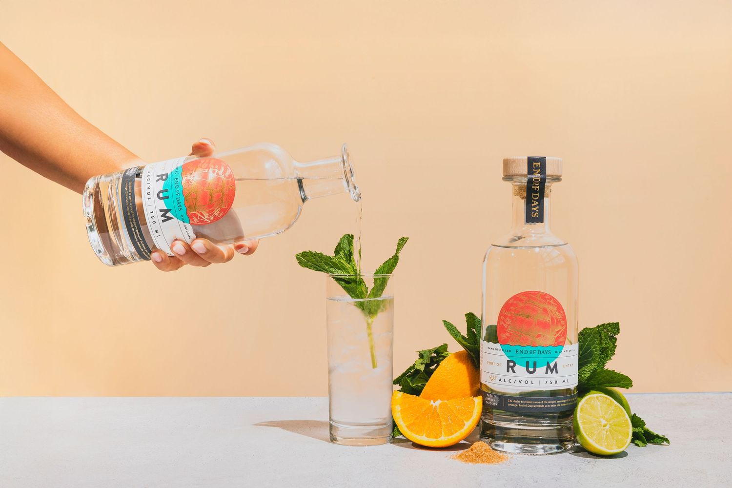Vibrant cocktail ingredients and garnishes displayed on peach colored background.