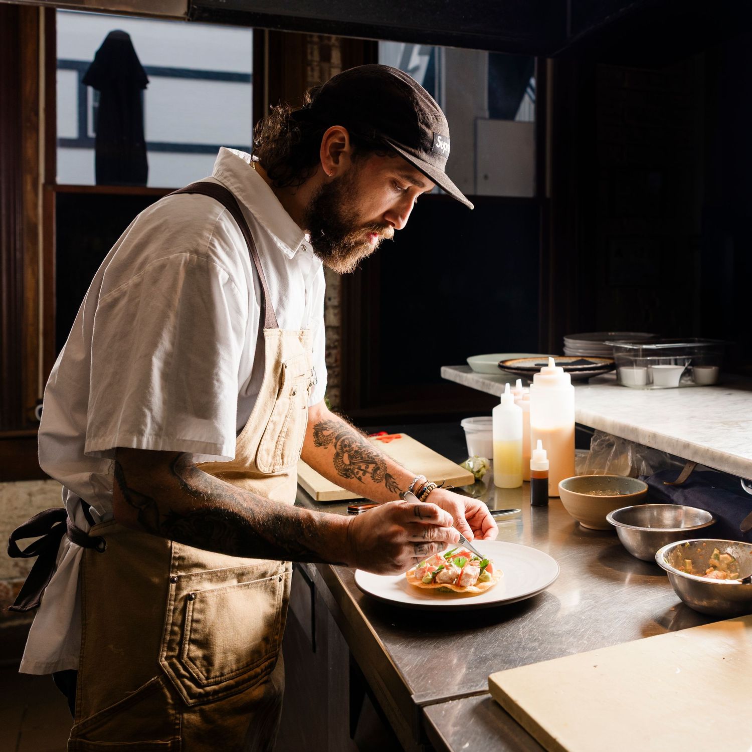 Chef working in dimly lit restaurant kitchen preparing food.