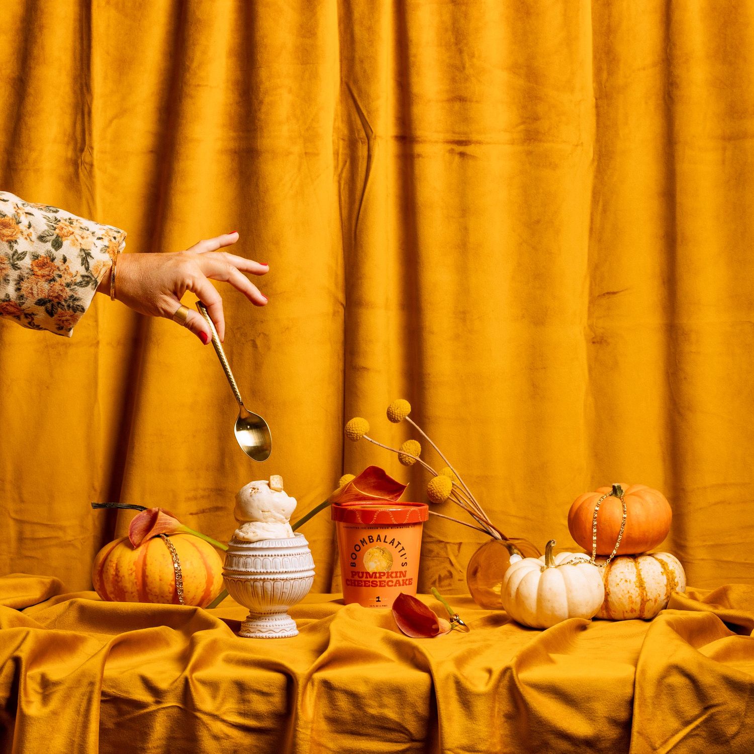 Autumnal display with orange curtain backdrop and decorative pumpkins on silk fabric.