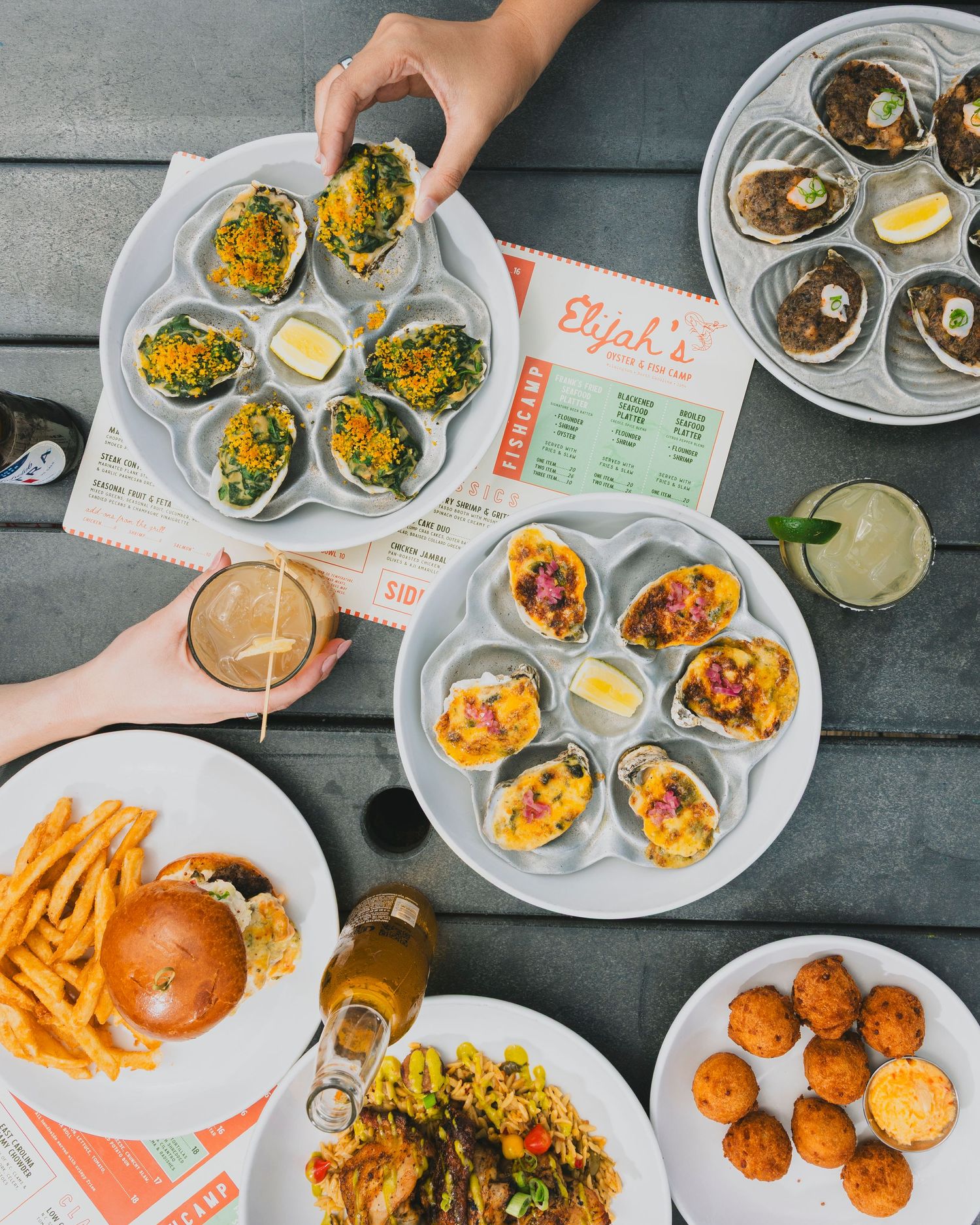 Overhead view of casual restaurant table spread with burgers, fries and various dishes.