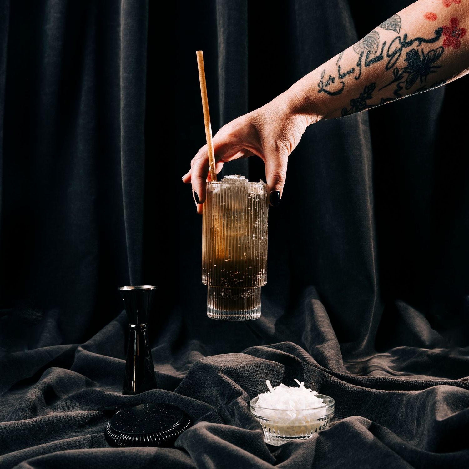 Dark moody cocktail preparation sequence with crystal glasses and ice against black background.