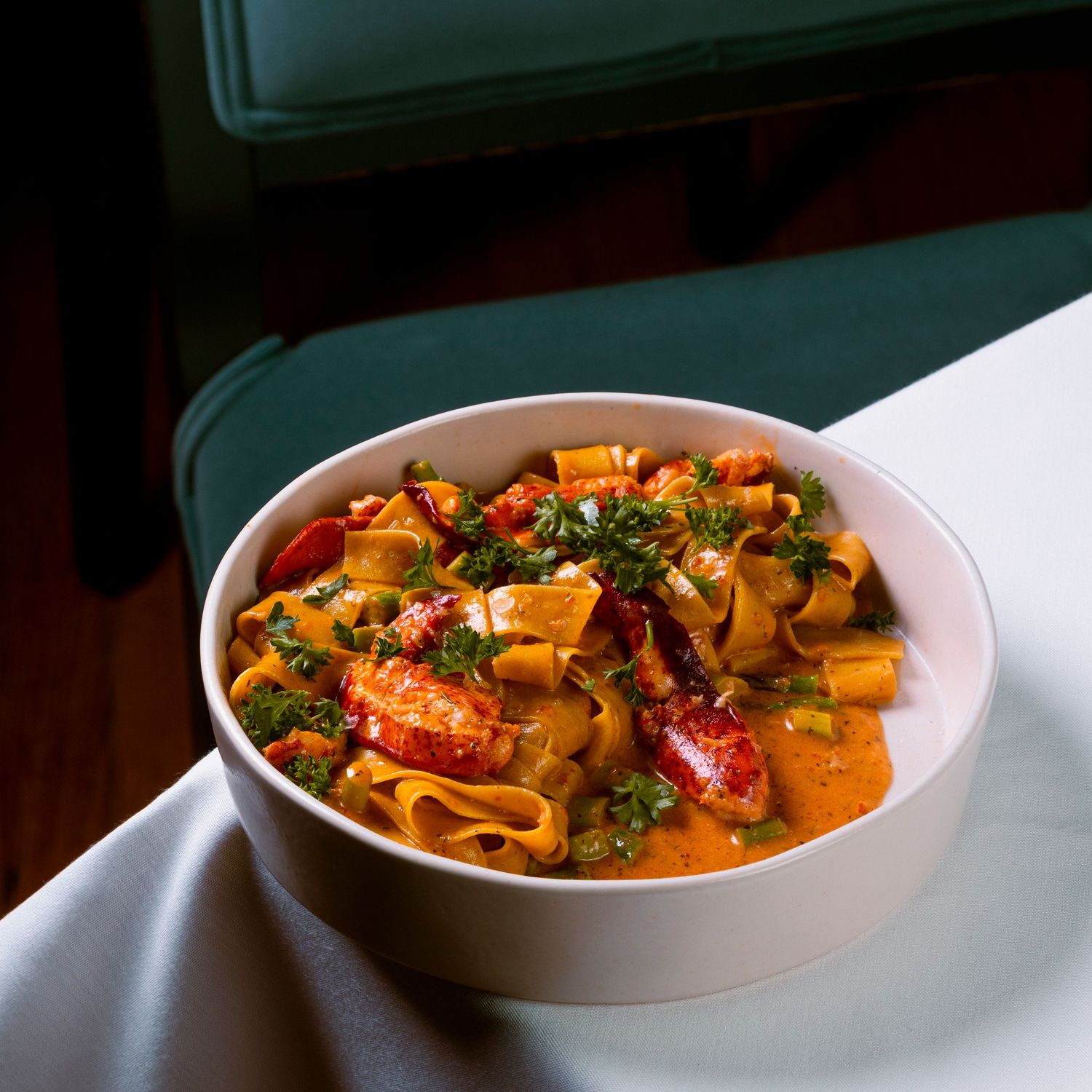 Creamy orange seafood pasta dish with lobster presented in elegant white bowls.