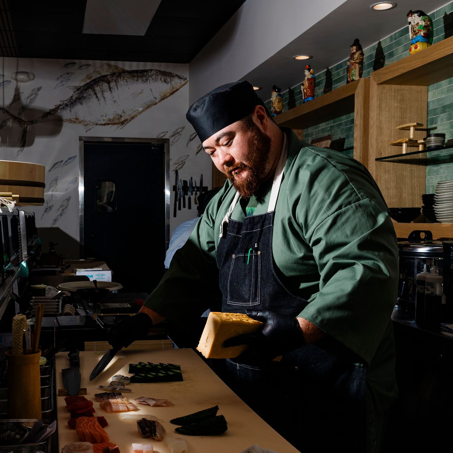 Dark and moody restaurant interior with staff working at dimly lit counters.