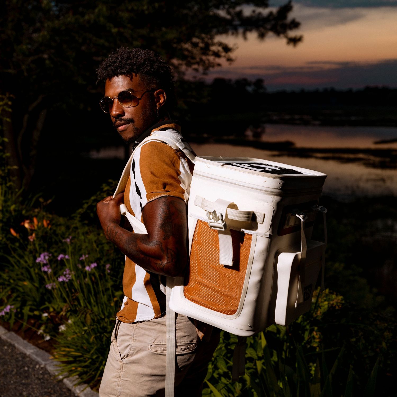 Coolers being carried along waterfront path during sunset gathering.