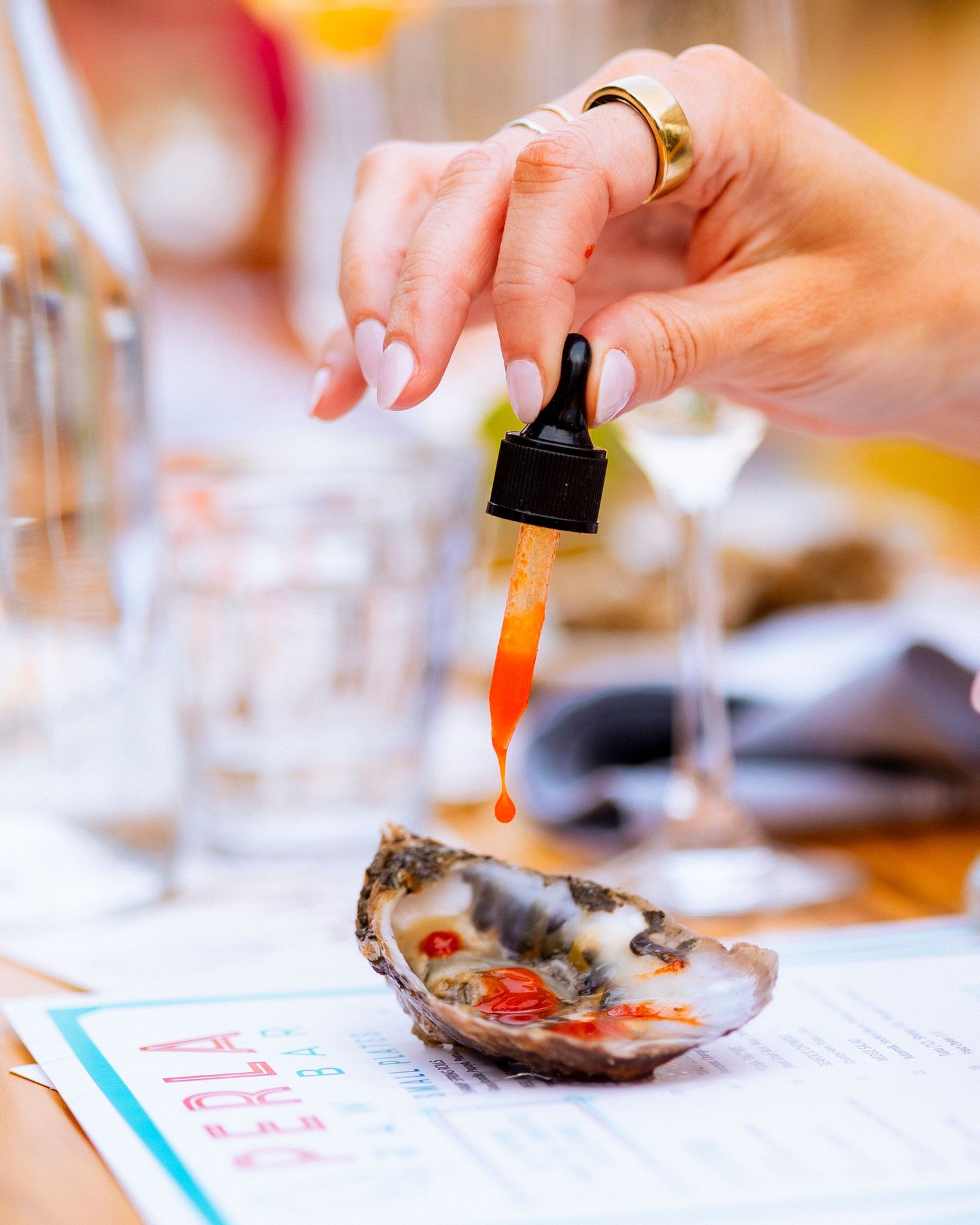 Close-up shots of hands garnishing and preparing fresh oysters on a white surface.