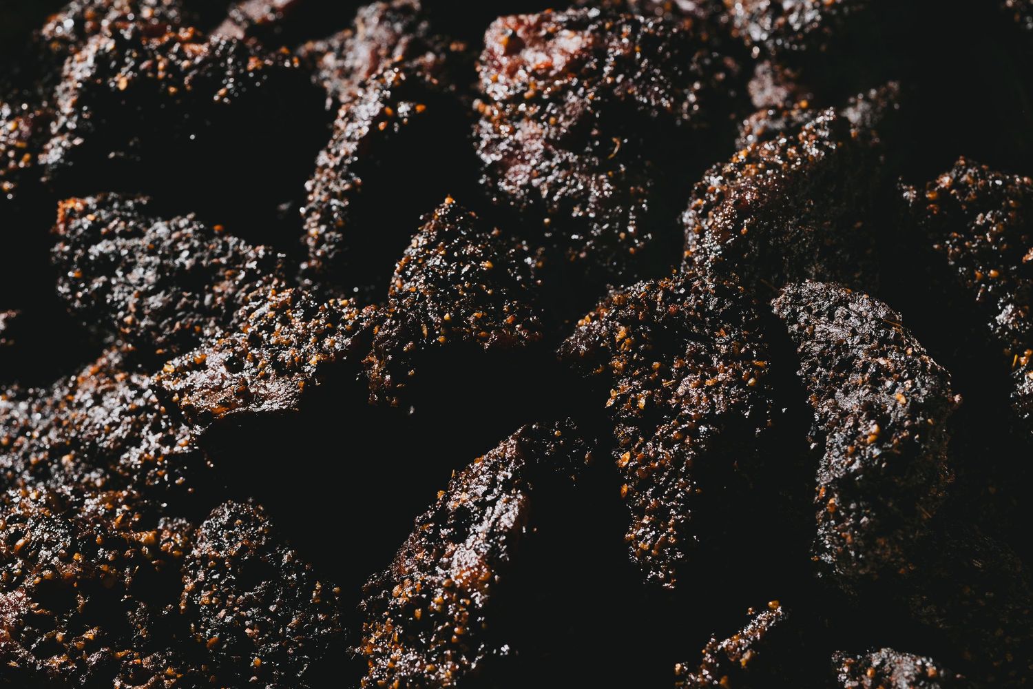 Close-up of charred and seasoned BBQ meat with a dark, crusty exterior.