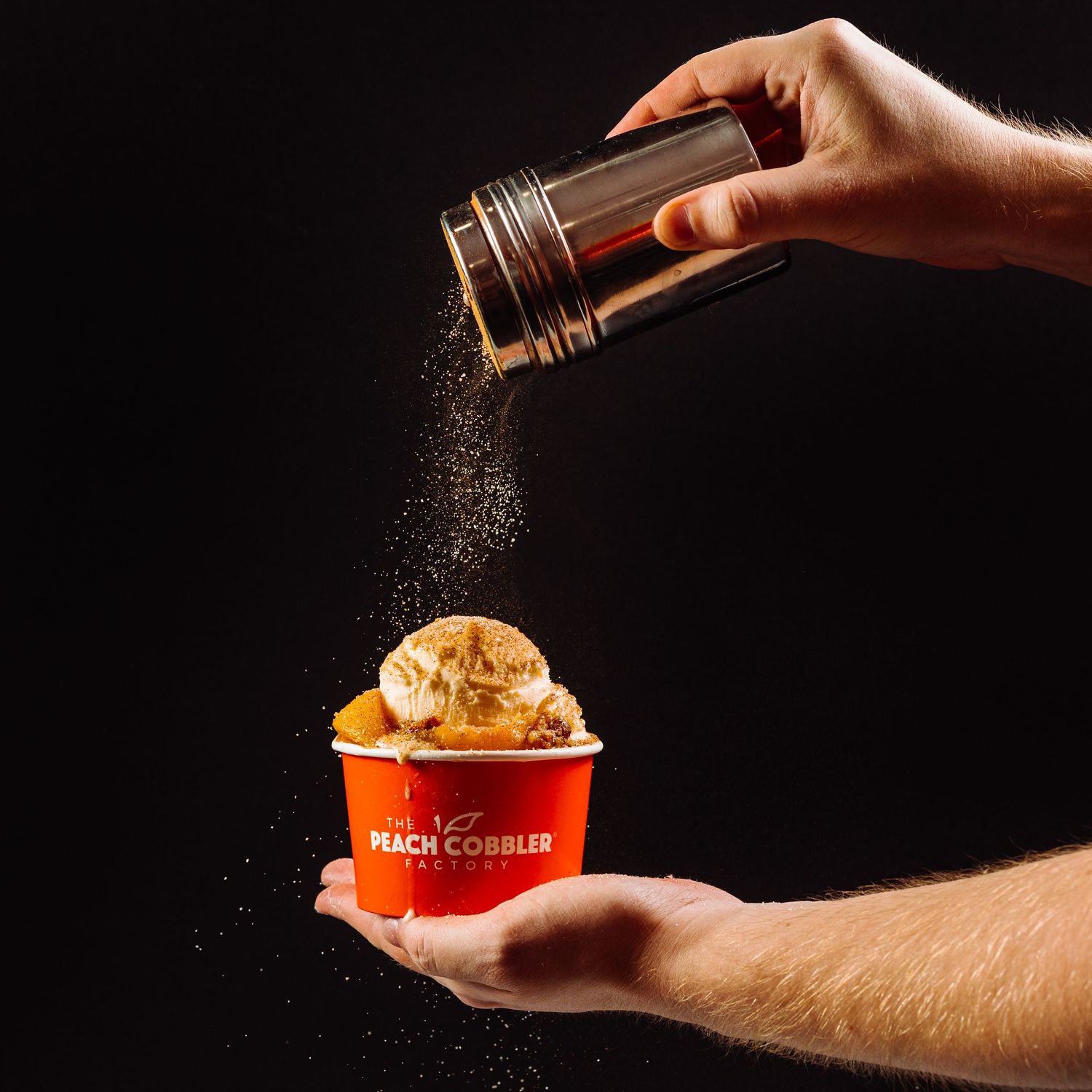 Dramatic sequence of spices being sprinkled over a peach dessert against a dark background.