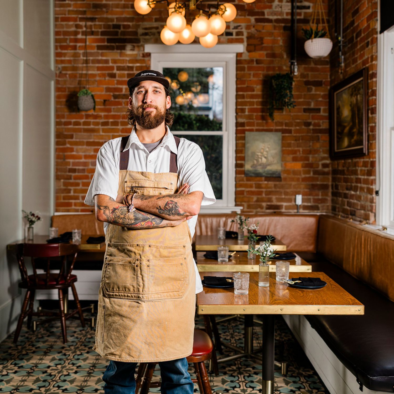 Restaurant interior with exposed brick walls, vintage lighting, and staff in aprons.
