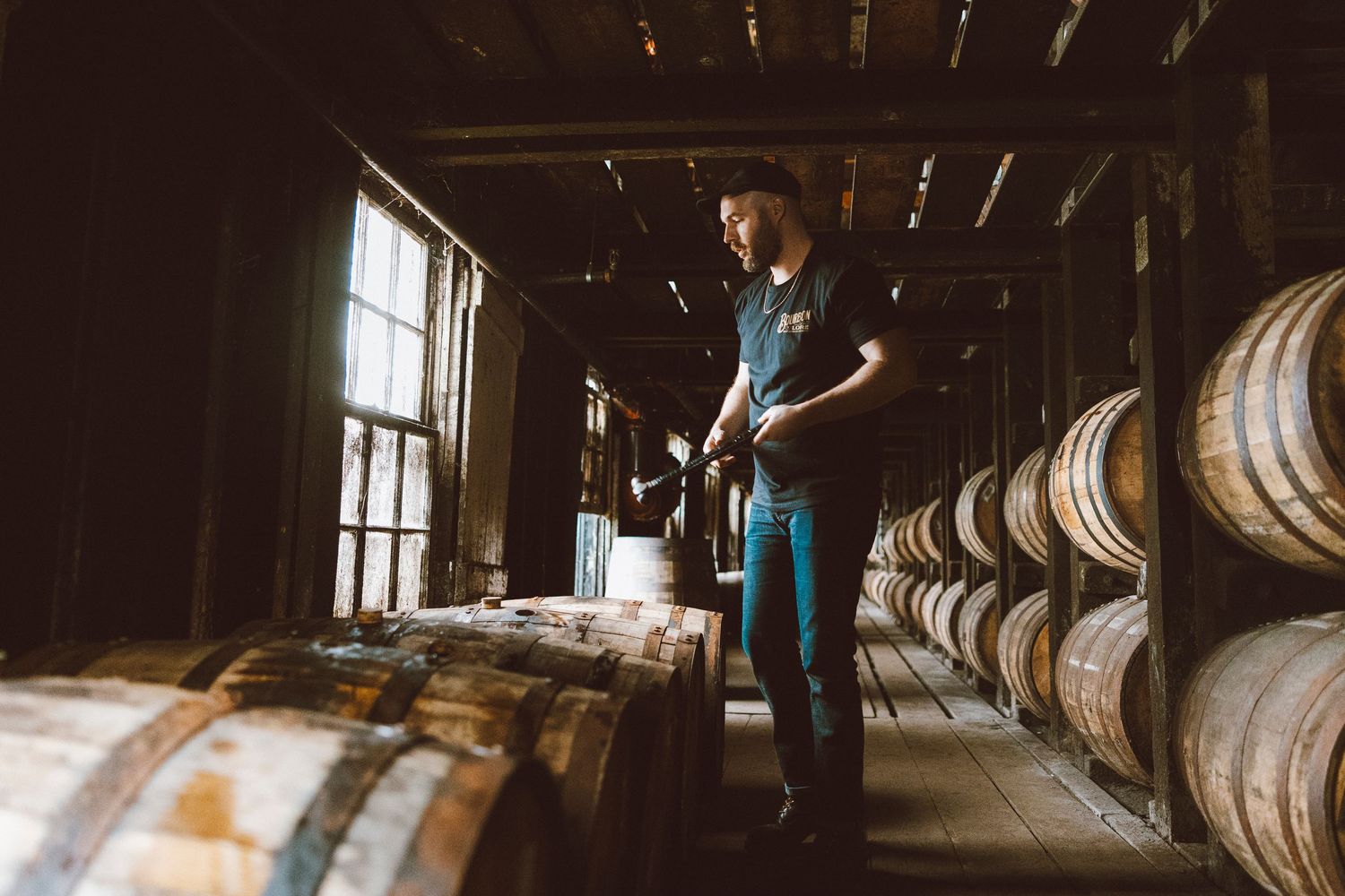 Wooden barrel storage room with whiskey barrels stacked along rustic walls.