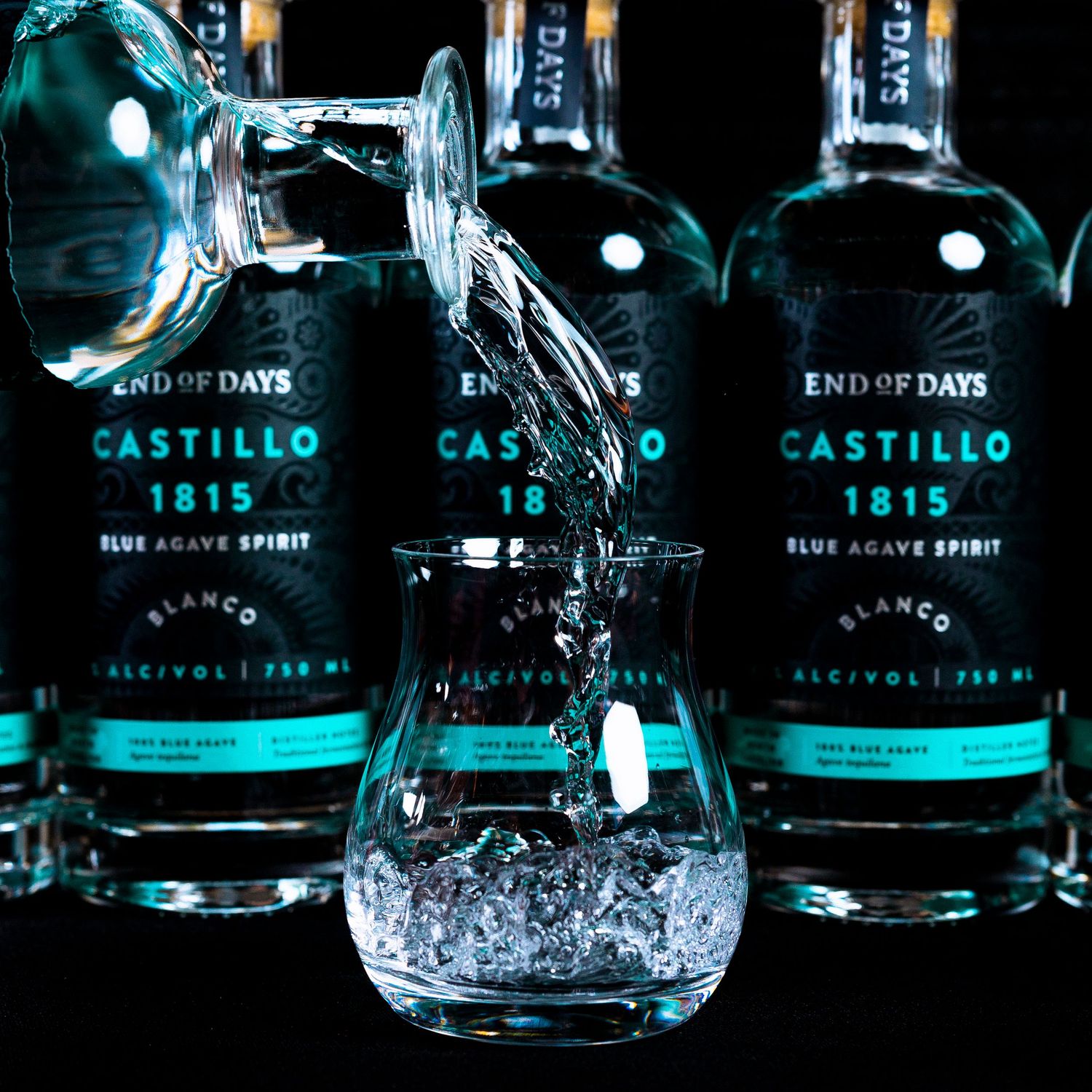 Row of illuminated tequila bottles displayed with dramatic blue lighting and reflections.